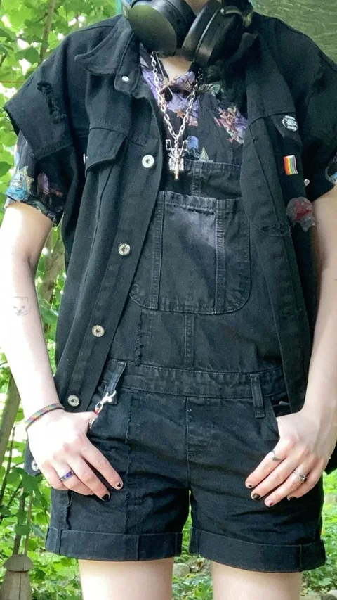 A man wearing a black jacket and shorts with headphones on.