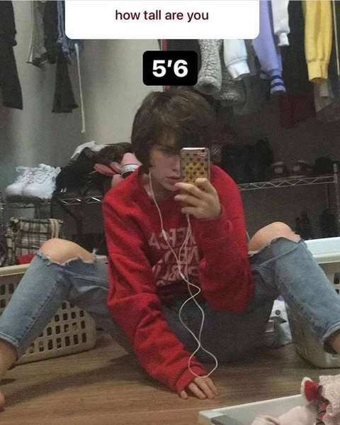 A woman sitting on the floor taking a picture of herself.