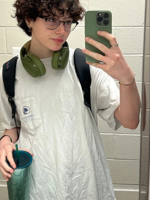 A woman in a white dress holding a green cup.