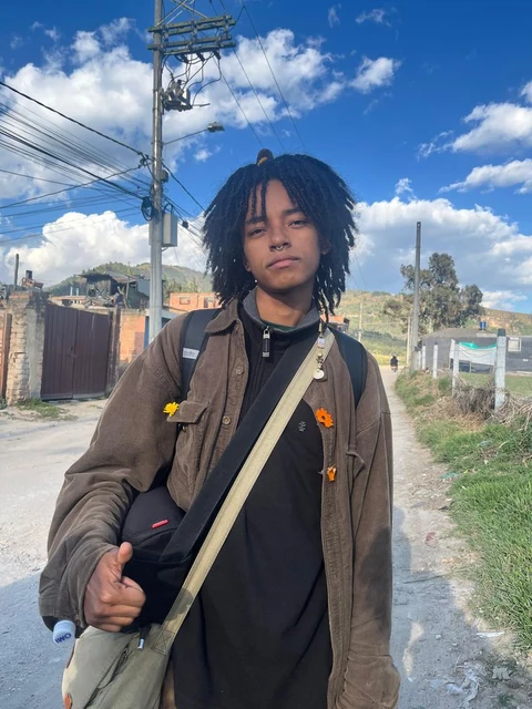 A man with dreadlocks standing on a dirt road.