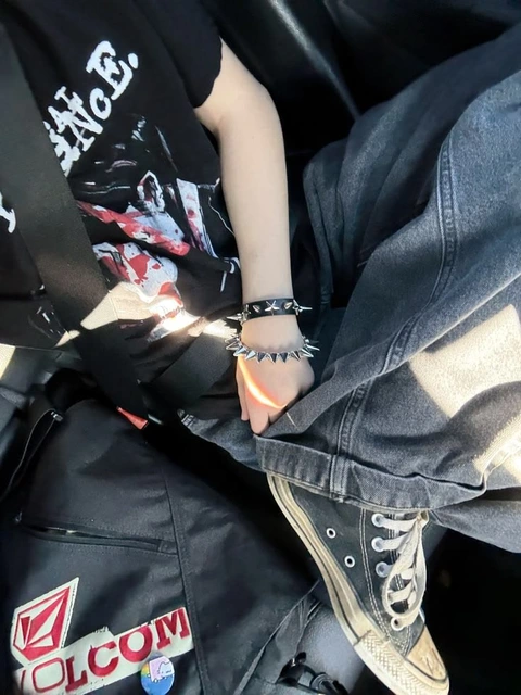 A pair of black and white converse sneakers with a pair of bracelets on their wrists.
