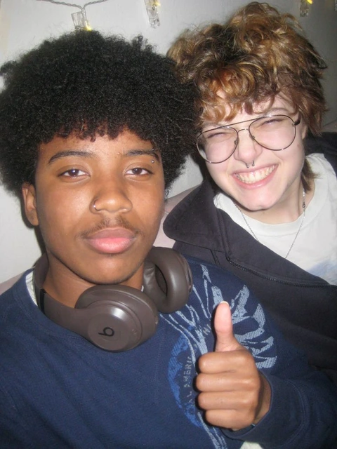 A couple of young men with curly hair and headphones.