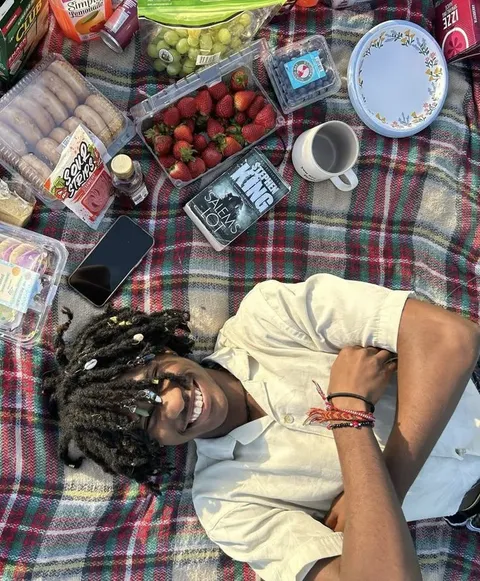 A man laying on a blanket with a bunch of food on it.