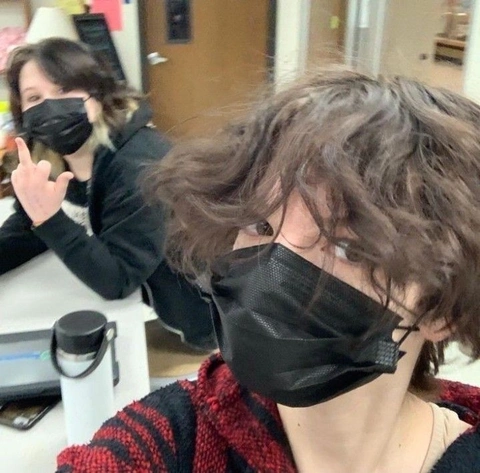 A woman wearing a black mask with a black bandana covering her mouth.