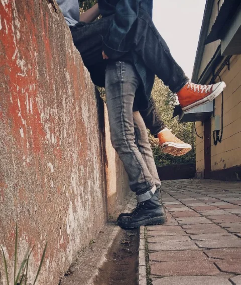 A couple of people standing next to each other on a sidewalk.