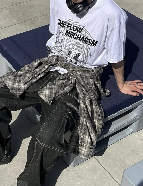 A man wearing a white shirt and a plaid skirt.