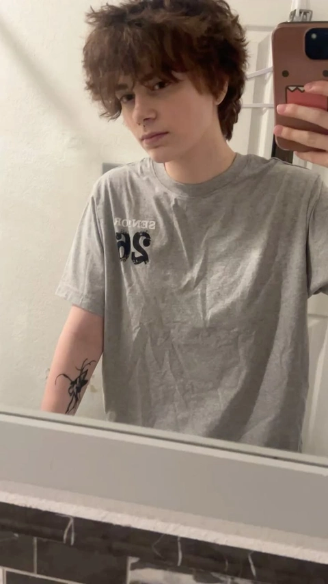 A young man with curly hair is taking a selfie.