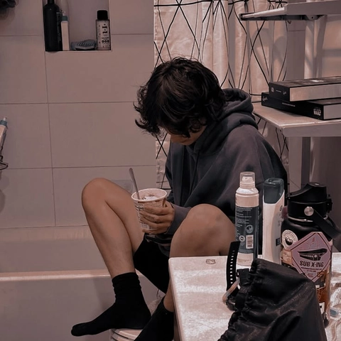 A man sitting on a toilet holding a cup of coffee.