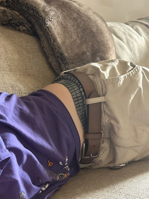 A man laying on top of a couch next to a backpack.