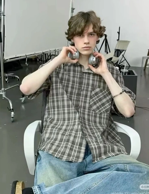 A young man sitting on a chair with headphones on.
