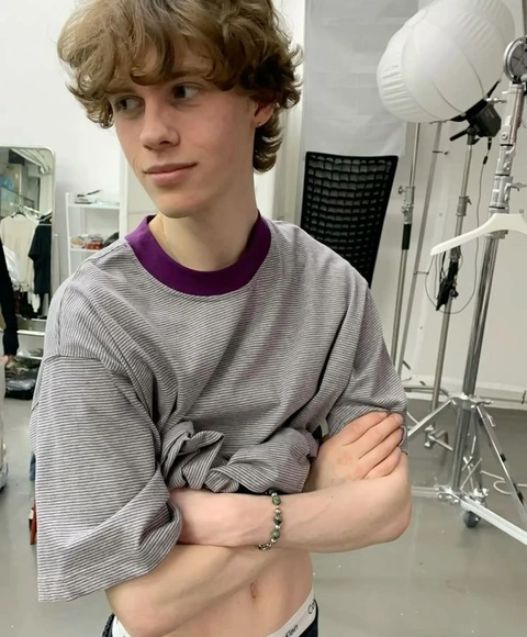 A young man with curly hair standing in front of a mirror.
