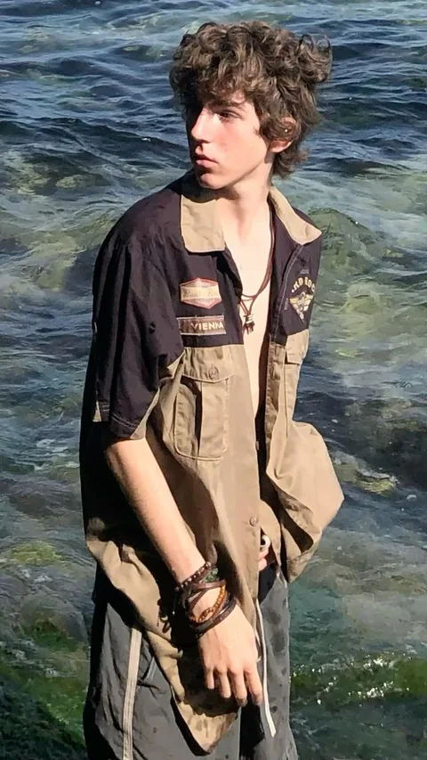 A young man with curly hair standing in the water.