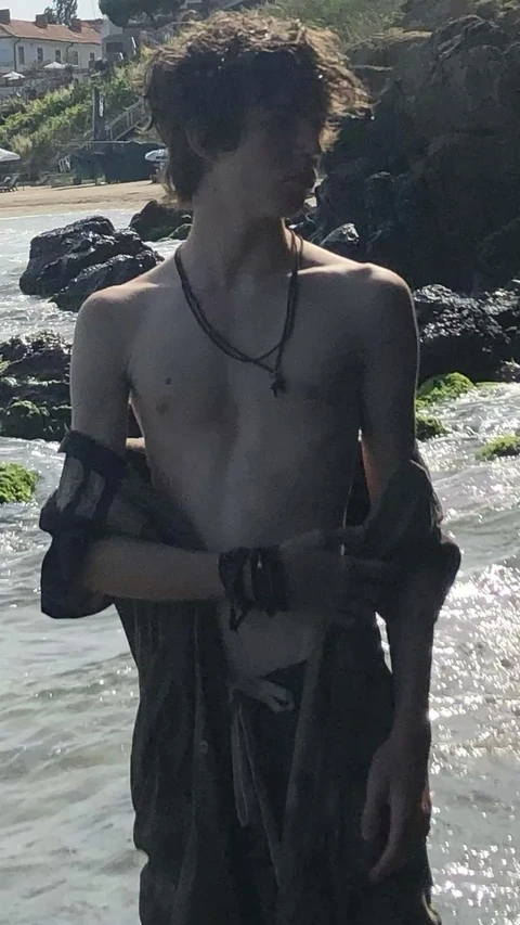 A man with curly hair standing in the water.
