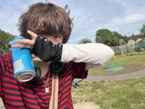 A man in a red and black striped shirt holding a can of soda.