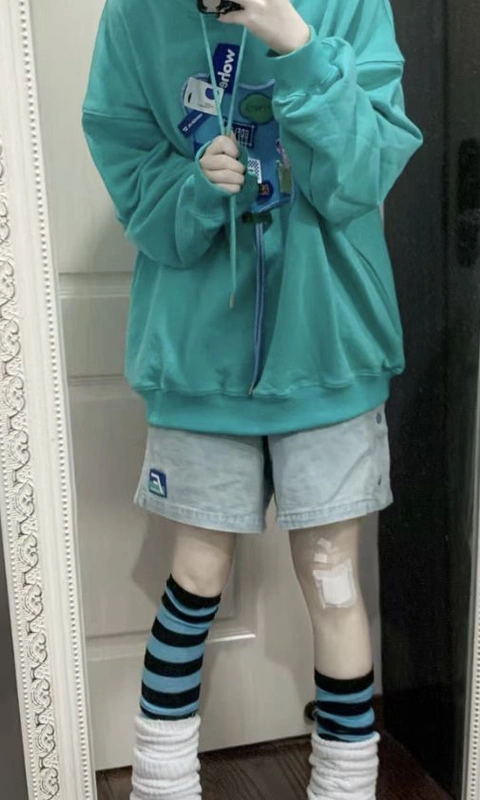 A mannequin wearing a blue hoodie and shorts holding a cell phone.