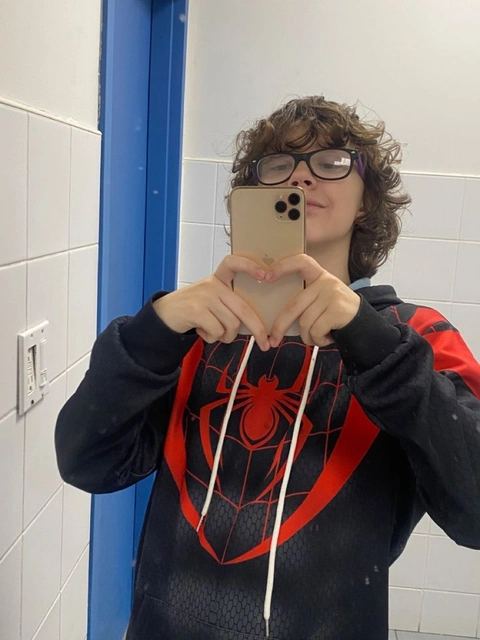 A man in a spiderman costume taking a selfie in a bathroom mirror.