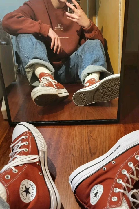 A reflection of a man sitting in a mirror with his feet in the mirror.