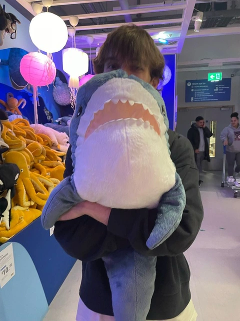 A man holding a stuffed shark in his hands.