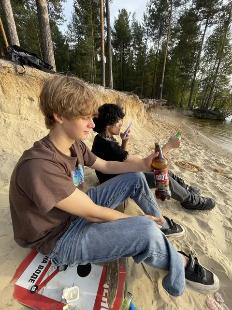 A group of young men sitting on top of a beach.