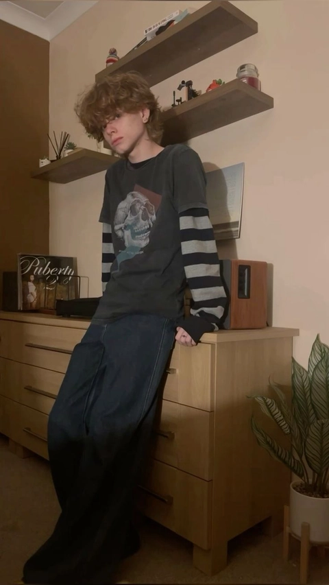 A young man sitting on top of a dresser.