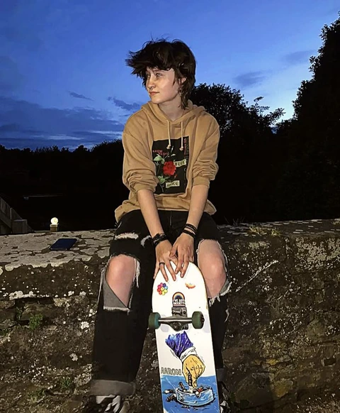 A young man sitting on top of a skateboard.