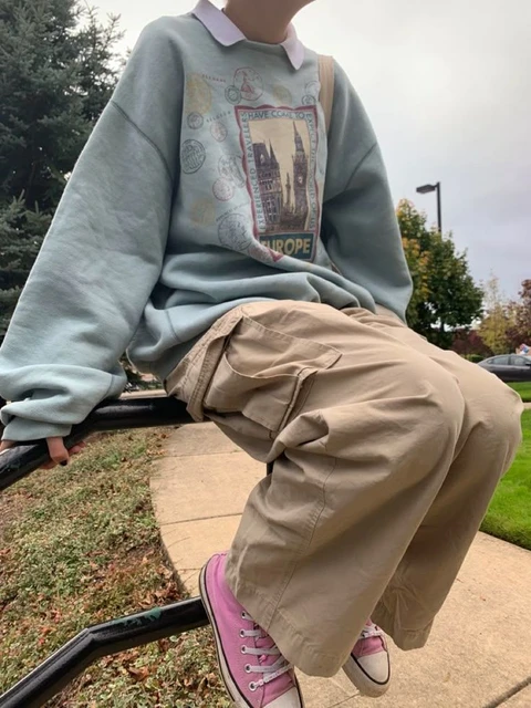 A mannequin wearing a sweater and pants sitting on a bench.