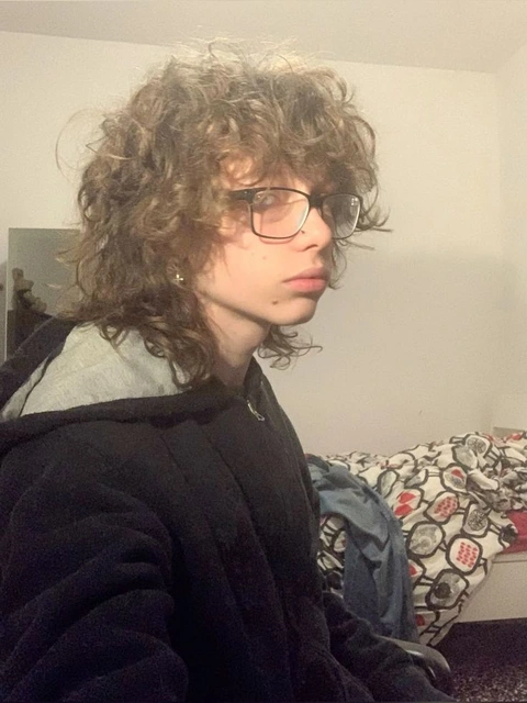A young man with curly hair wearing glasses.