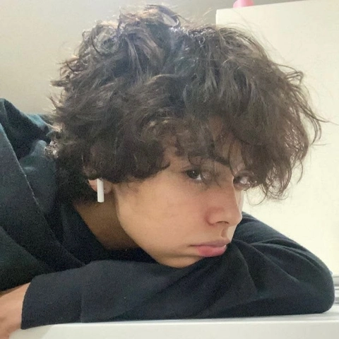 A woman with curly hair is looking at the camera.