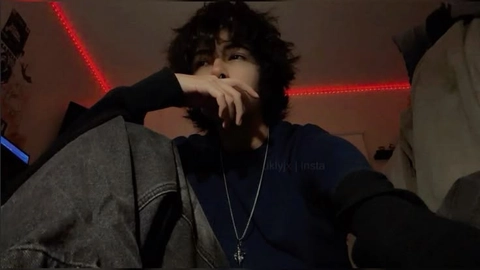 A man with curly hair sitting in front of a television.
