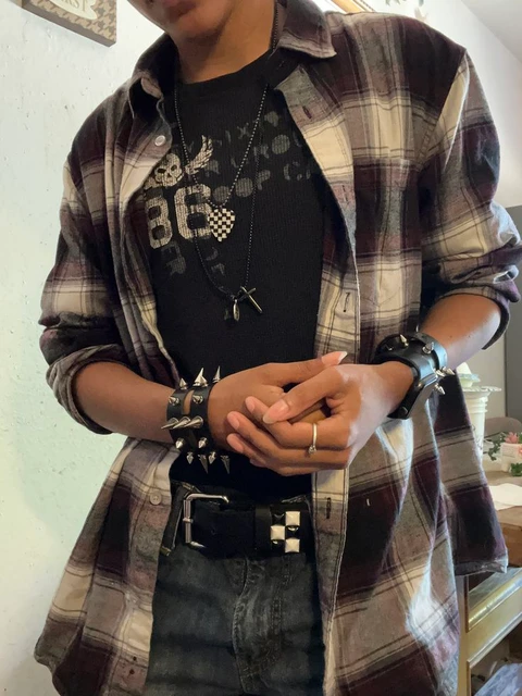 A man in a plaid shirt and jeans holding his hands together.