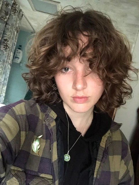 A young girl with curly hair is looking at the camera.