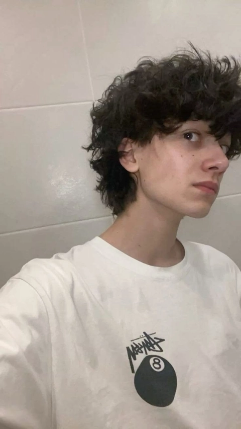 A young man with curly hair wearing a white shirt.