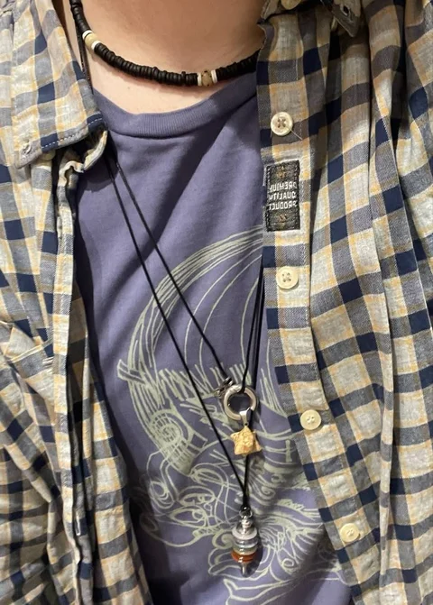 A close up of a person wearing a shirt and a necklace.