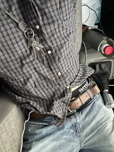 A man sitting in the back seat of a car with a belt.