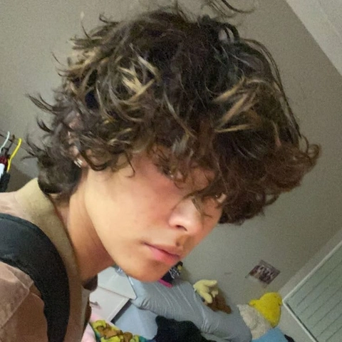 A young boy with curly hair and a stuffed animal.