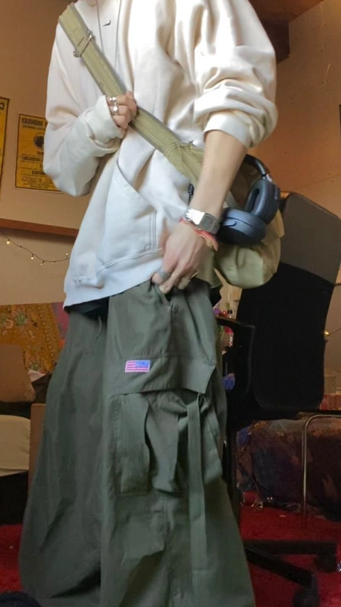 A man in a white shirt and green pants holding a pair of dumbbells.