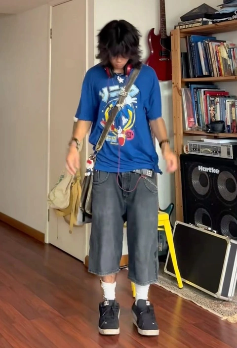 A man in a blue shirt and gray pants walking down a hallway.