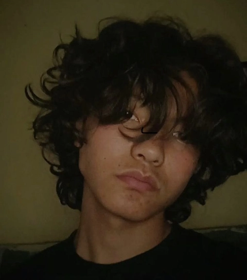 A young boy with curly hair and a black shirt.