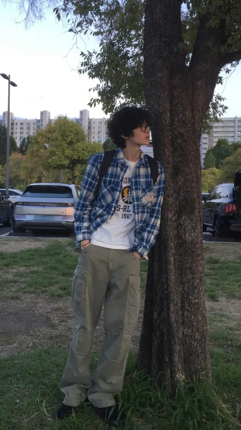 A man leaning against a tree in a park.