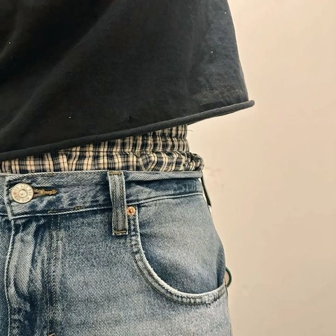A pair of jeans with a black shirt on top of them.