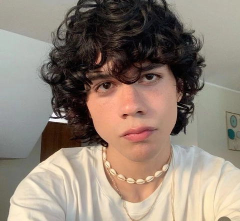 A young man with curly hair wearing a white shirt.