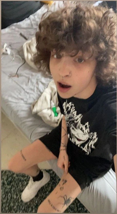 A little girl with curly hair sitting on a bed.