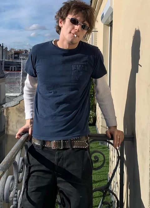 A man standing on a balcony smoking a cigarette.