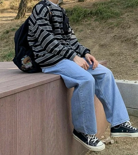 A man sitting on top of a wooden bench.