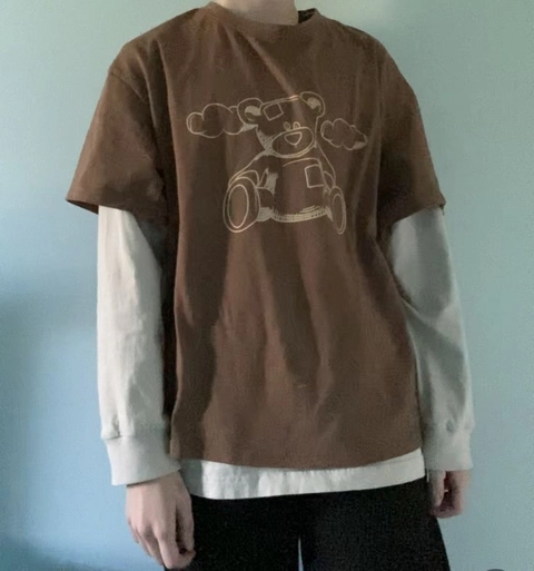 A man wearing a brown shirt with a teddy bear on it.