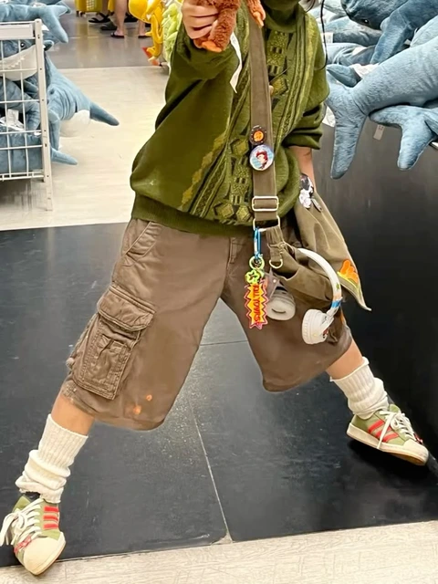 A man in a green jacket and brown pants holding a stuffed animal.