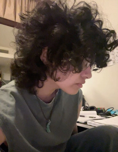A woman with curly hair sitting on a chair.