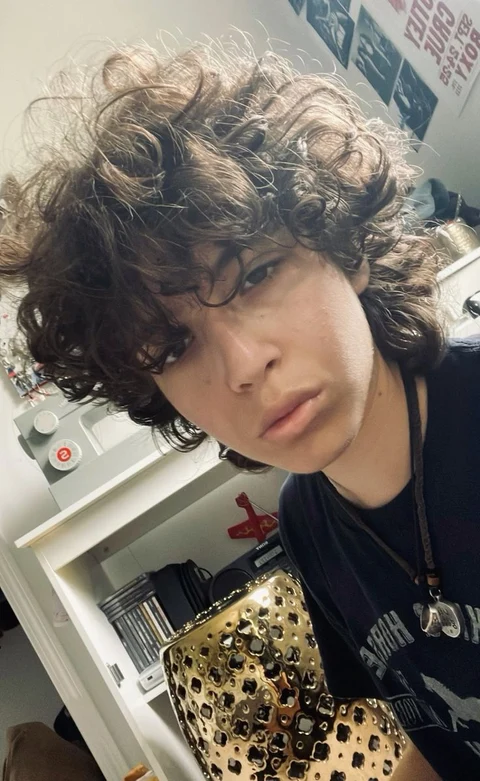 A young man with curly hair posing for a picture.