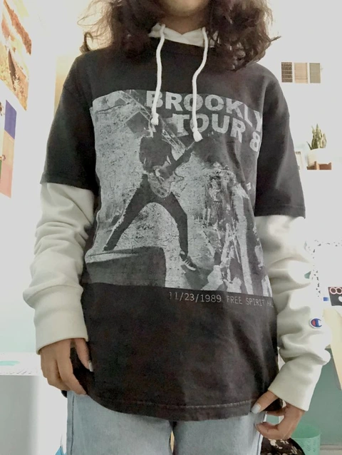 A man with long hair wearing a hoodie and jeans.